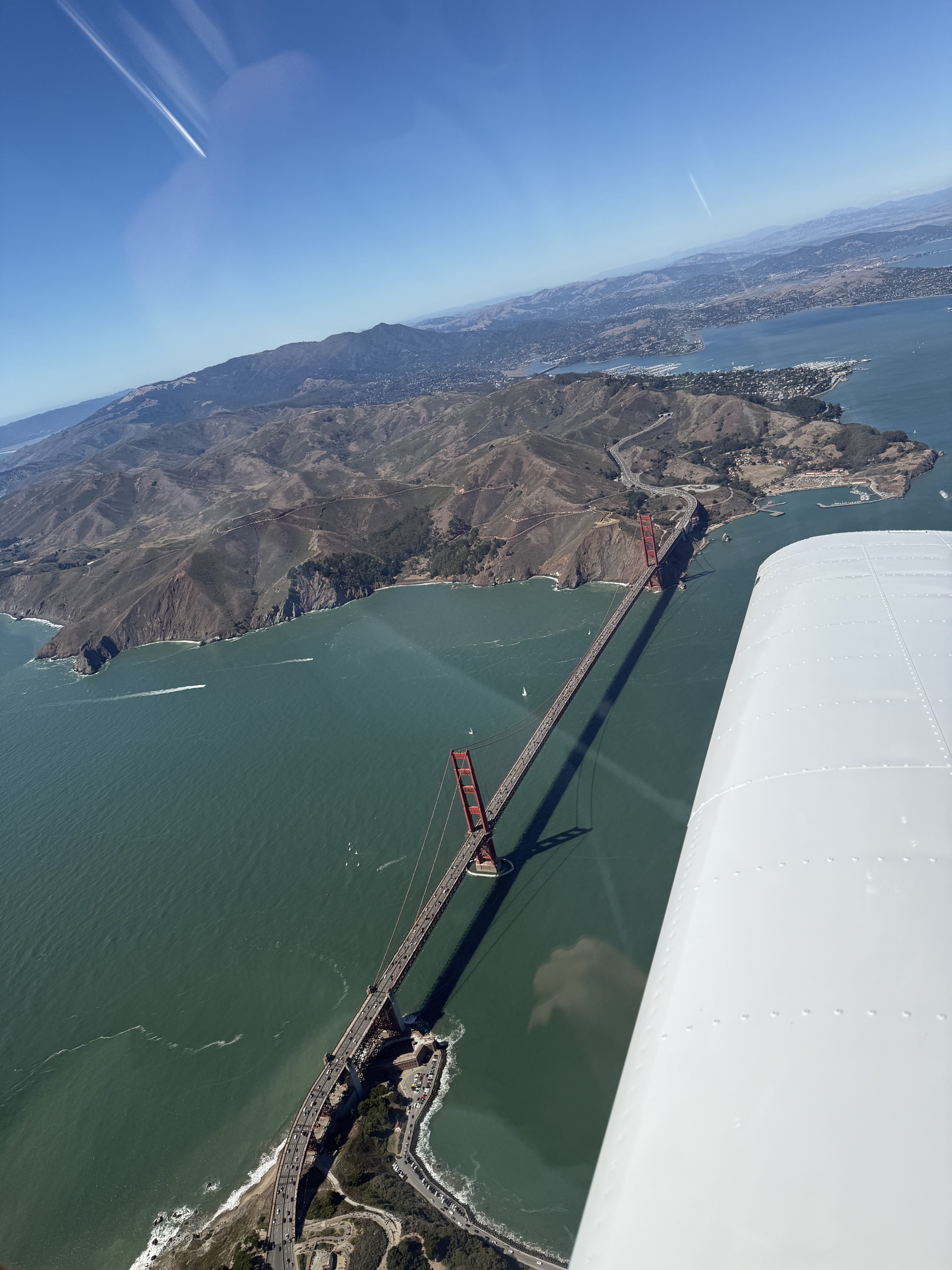 Golden Gate Bridge and coastal hills beside the airplane wing