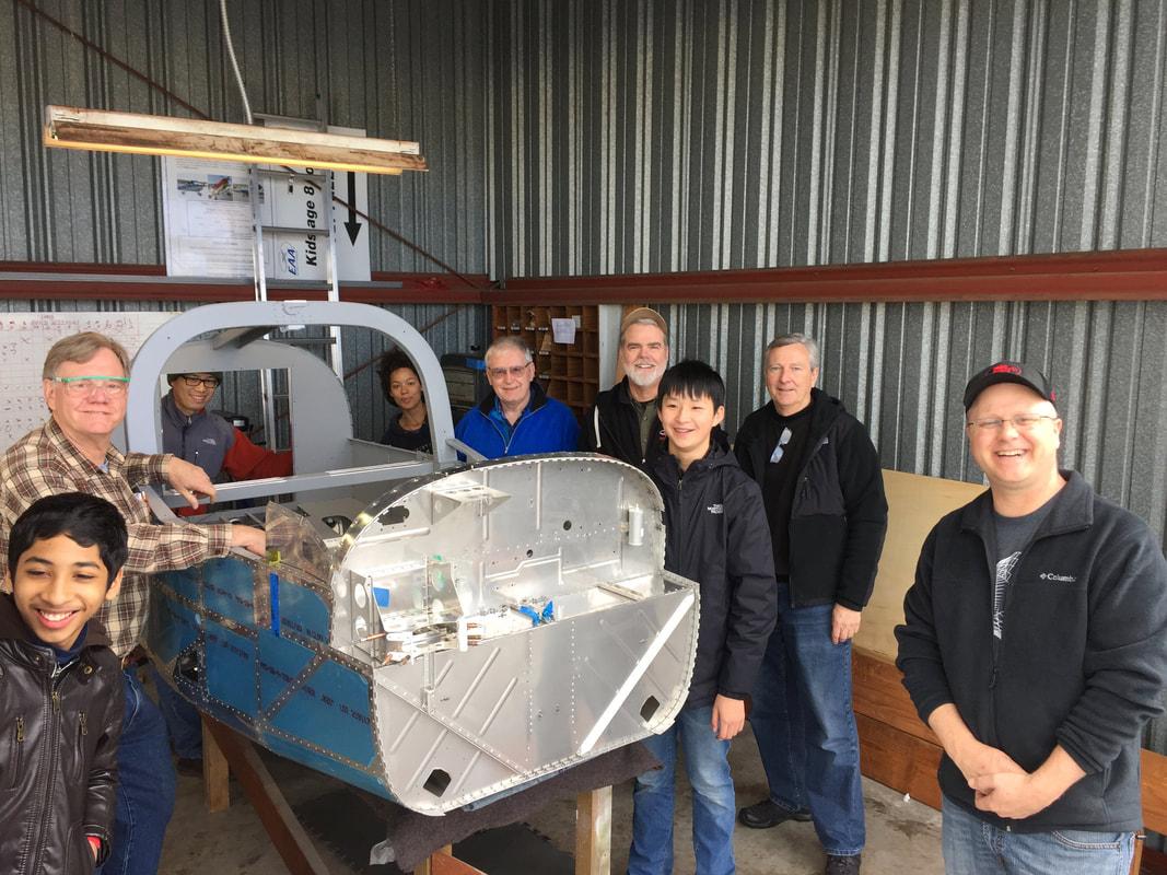 Young aviators and mentors gathered around the unfinished RV-12 fuselage