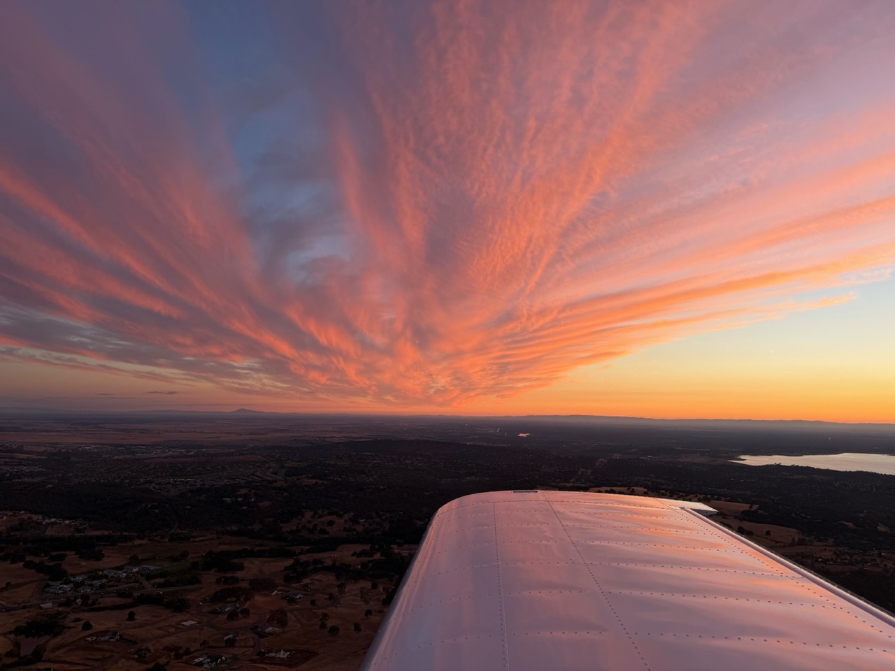 Pink sunset clouds above an airplane wing