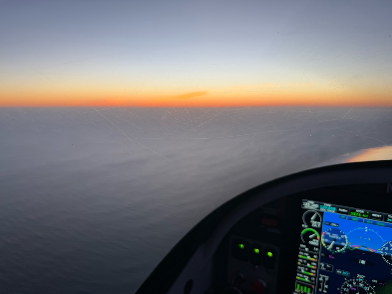 An orange horizon above a blanket of clouds